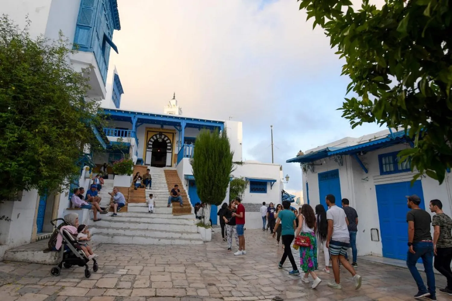 Tunisians walk in a street in the village of Sidi Bou Said on May 30, 2020, after shops reopened following a three-month shutdown due to COVID-19. (AFP)