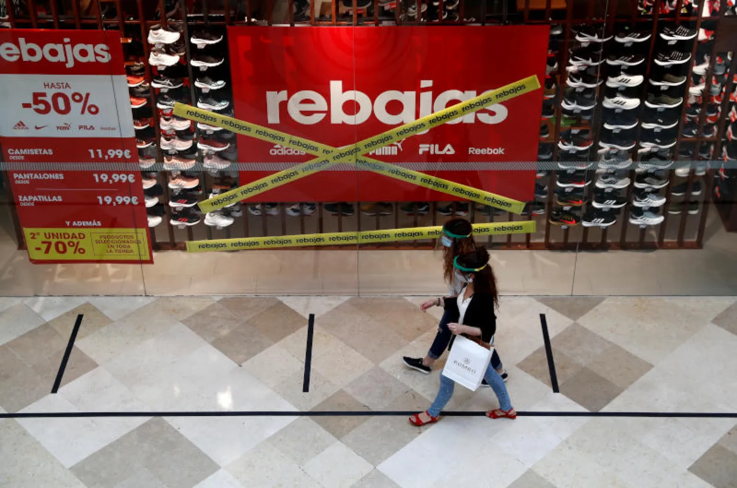 سيدتان ترتديان قناعي وقاية داخل مركز تسوق خارج مدريد (رويترز)