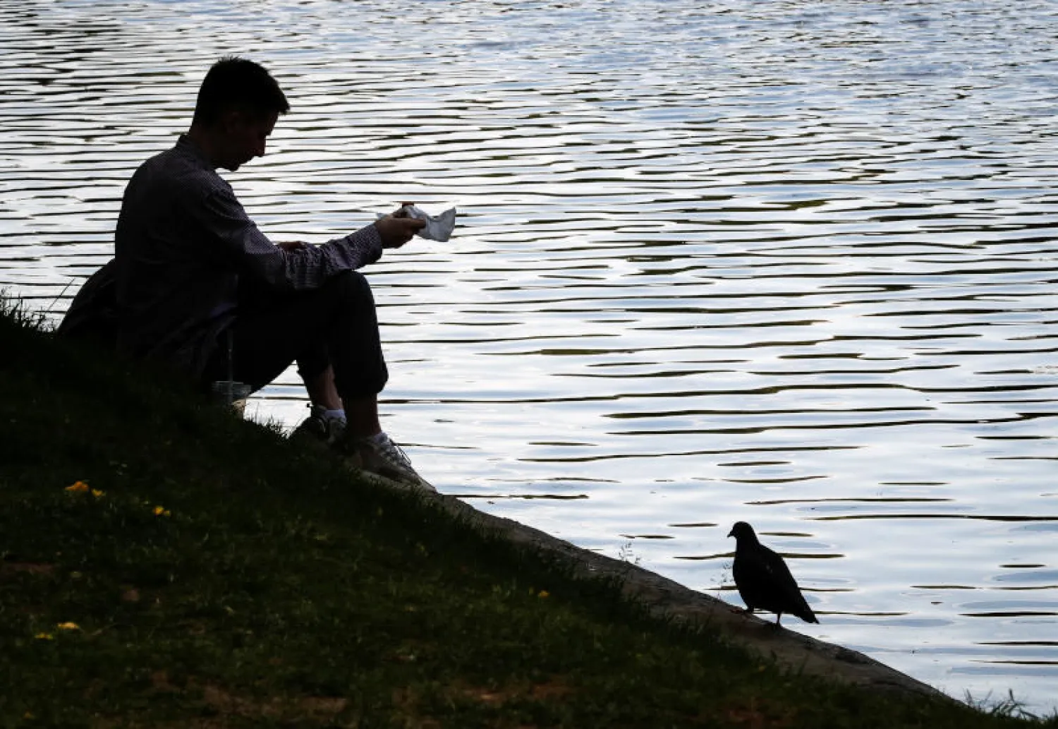 رجل يجلس بالقرب من بحيرة في موسكو (رويترز)