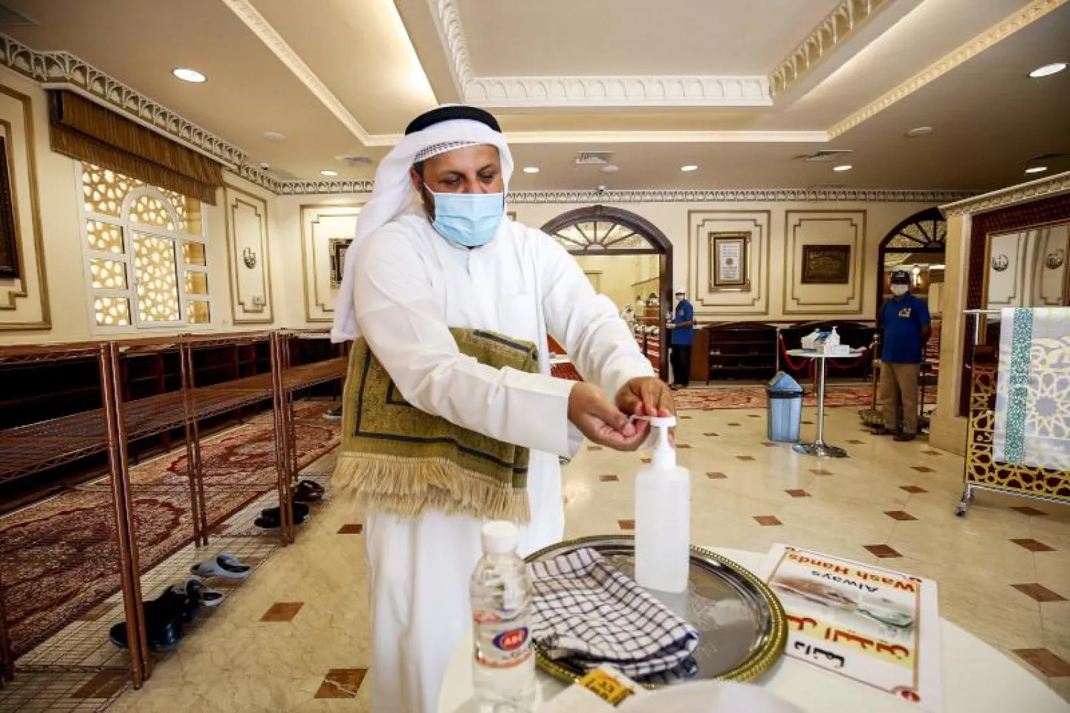 مواطن كويتي يعقم يديه قبل دخوله لتأدية الصلاة في أحد المساجد بالكويت (أ.ف.ب)