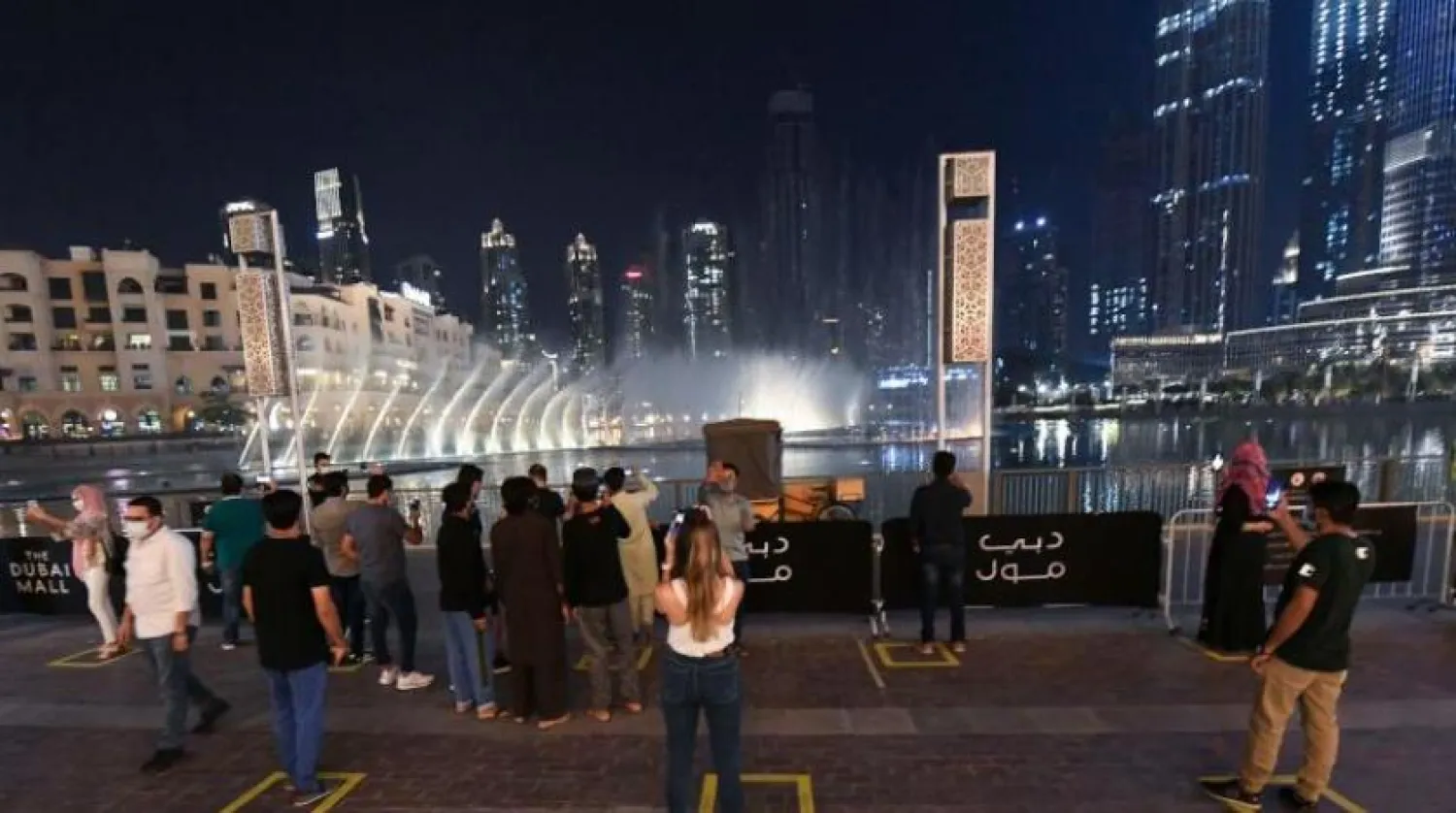Dubai'deki çeşme şovunu sosyal alan taahhüdüyle izleyen insanlar (AFP)