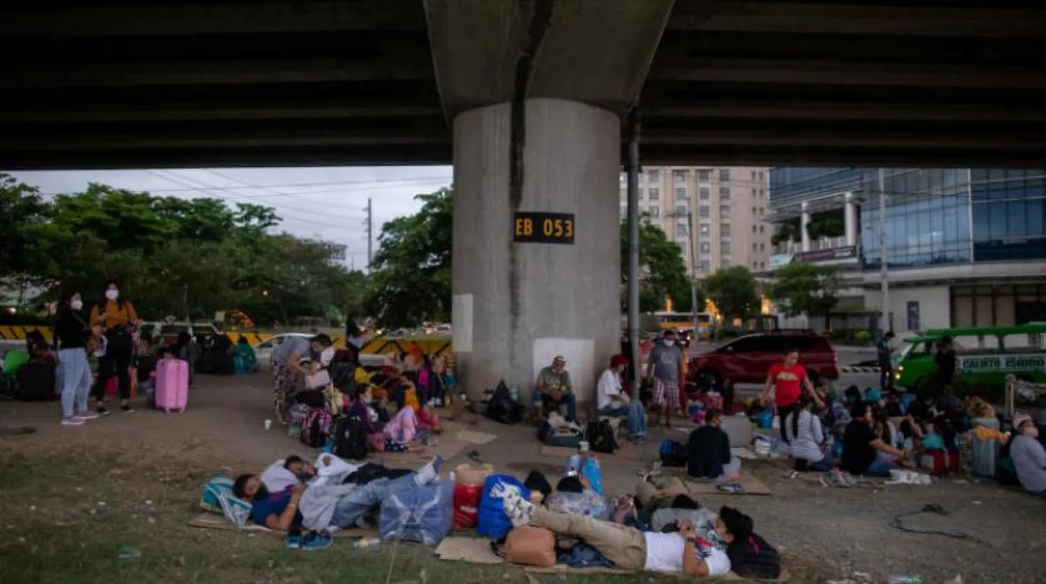 Yüzlerce kişi Manila Havaalanı yakınındaki bir otoyolun kenarında oturuyor (Reuters) 
