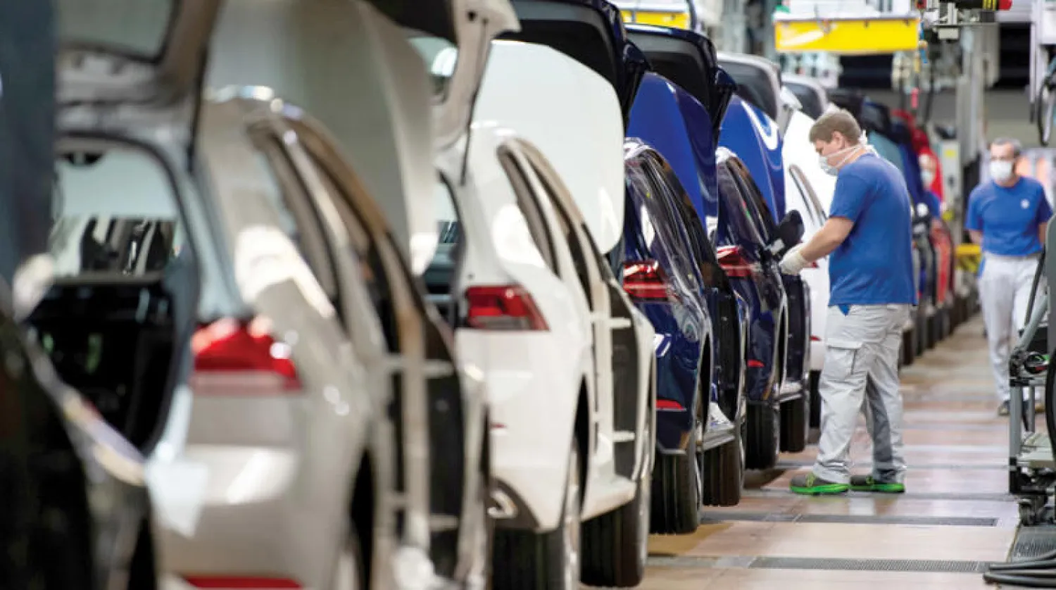 عاملان يضعان كمامتين واقيتين في خط تجميع «فولكسفاغن» بعد أن أعادت الشركة تشغيل أكبر مصنع للسيارات في أوروبا في أعقاب الإغلاق الصحي (رويترز)