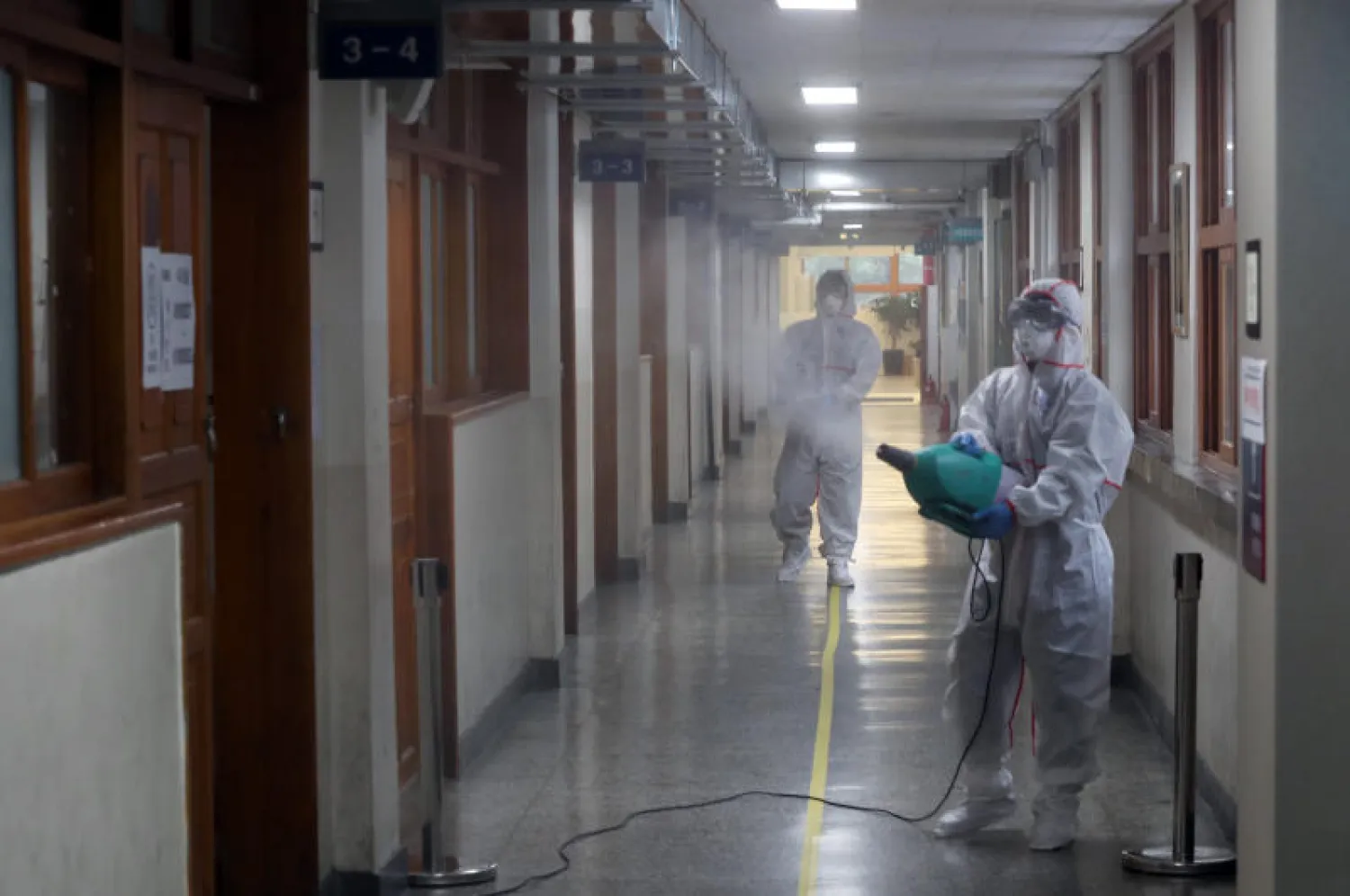 عاملان يقومان بتطهير المباني للوقاية من «كورونا» (د.ب.أ)