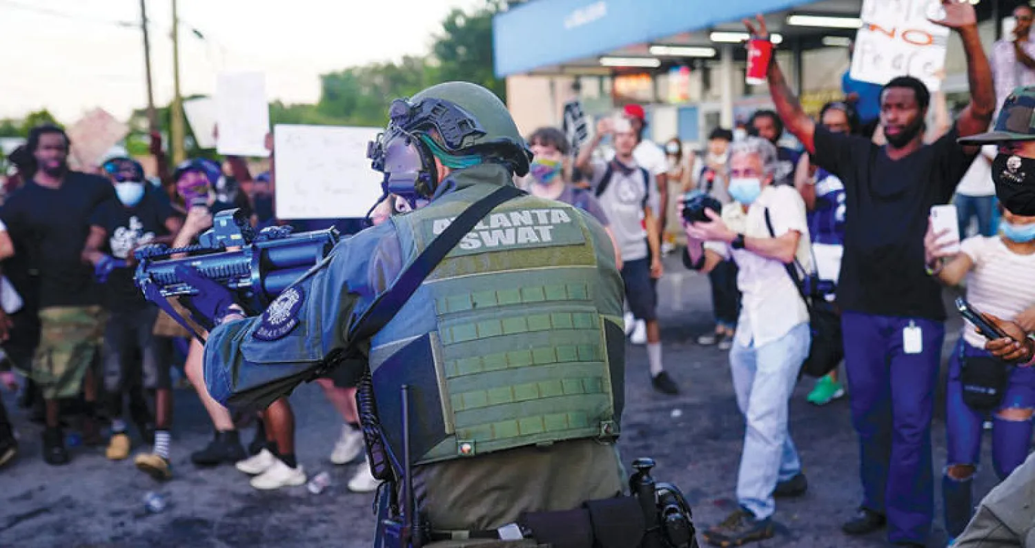 عنصر من القوات الخاصة يشهر سلاحه السبت أمام مظاهرة ضد قتل بروكس في أتلانتا (رويترز)