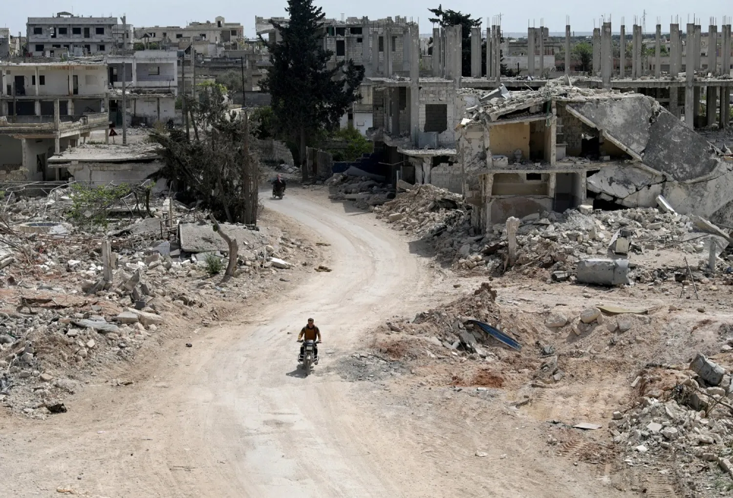 A man rides a motorbike past damaged buildings in the town of Nairab, Idlib region, Syria April 17, 2020. (Reuters)