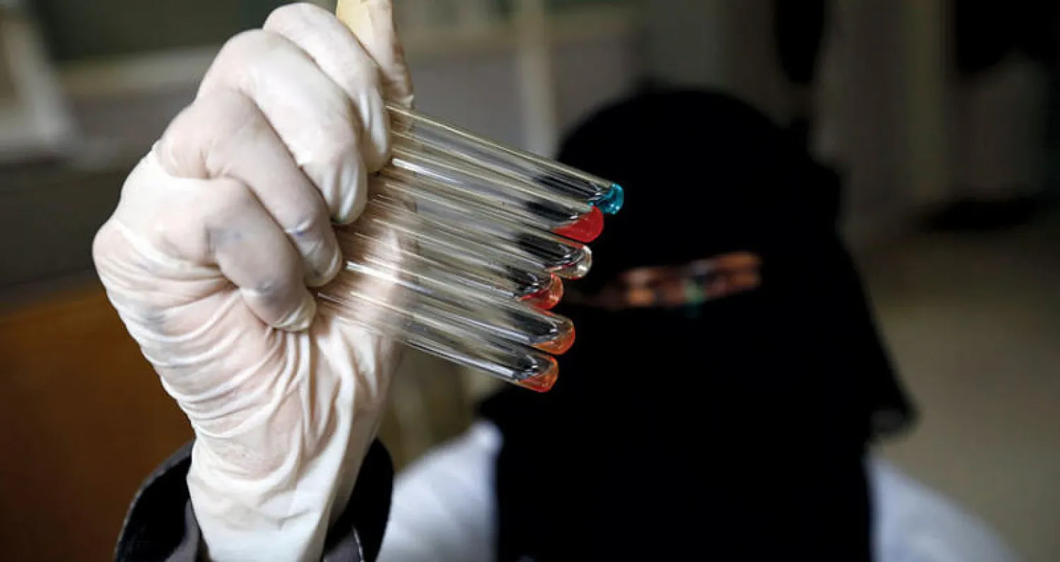 يمنية تعمل في مختبر طبي تحمل عينات تبرع بالدم بأحد مستشفيات صنعاء (إ.ب.أ)