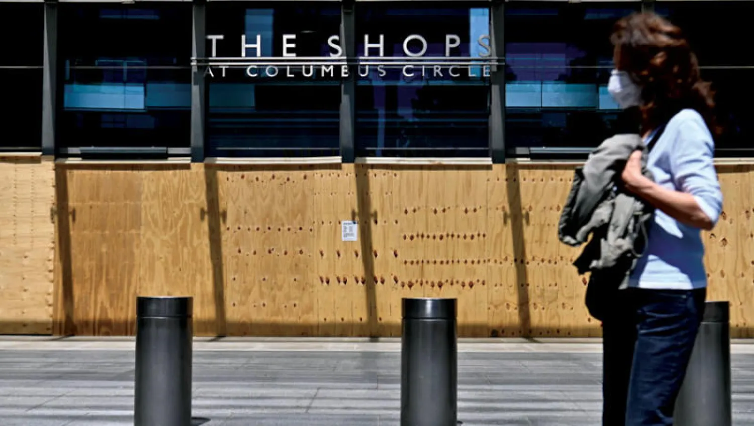 أميركية تسير بجانب مركز تجاري مقفل في مدينة نيويورك التي تُعدّ إحدى بؤر تفشي فيروس «كورونا» (أ.ف.ب)