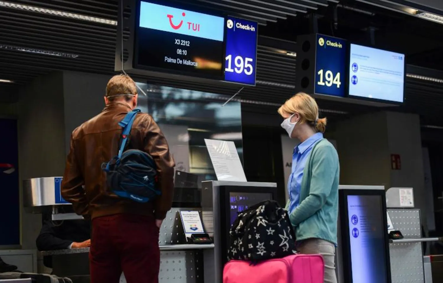 مسافران يرتديان كمامتين في مطار دوسلدورف بألمانيا (أ.ف.ب)