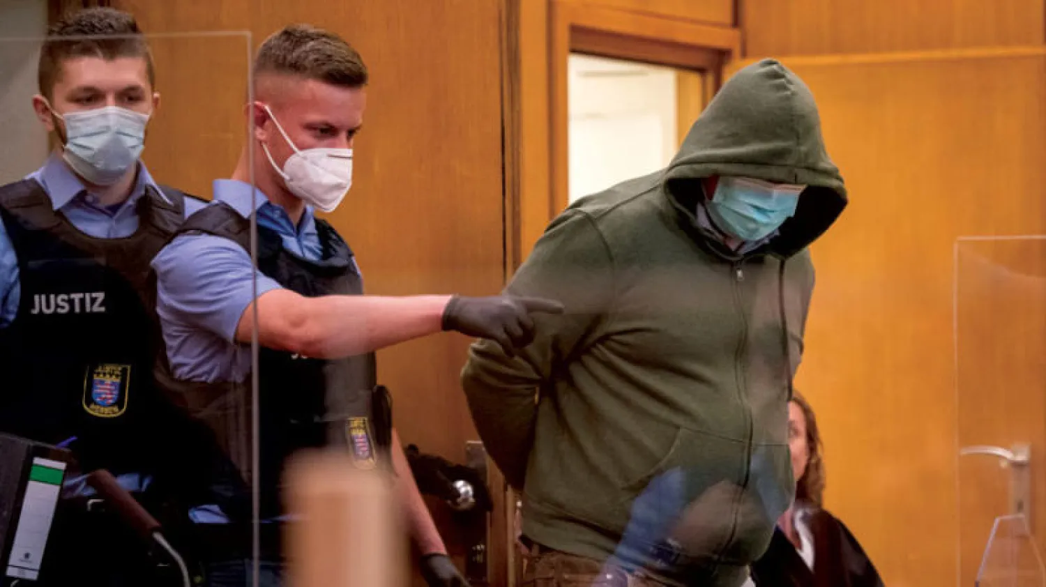 الجاني «ماركوس.ه» والحراس يرتدون الكمامات في محاكمة مقتل السياسي فالتر لوبكه المنتمي لحزب المستشارة أنجيلا ميركل بالمحكمة العليا بمدينة فرنكفورت أمس (رويترز)
