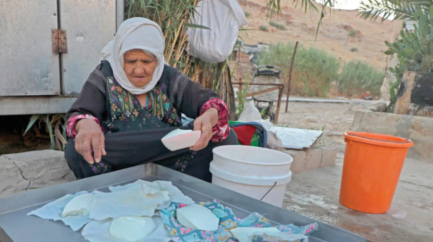 مسنّة فلسطينية تصنع أجباناً أمس في مزرعة بقرية في غور الأردن (أ.ف.ب)