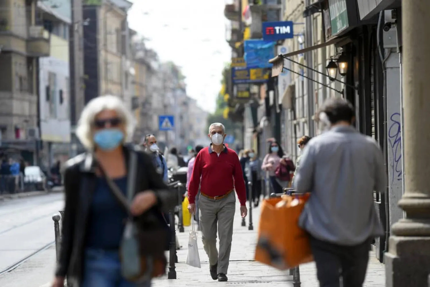 People wearing protective masks walk in an increasingly busy street, amid the coronavirus disease (COVID-19) outbreak, in Milan, Italy April 18, 2020. | REUTERS/Daniele Mascol