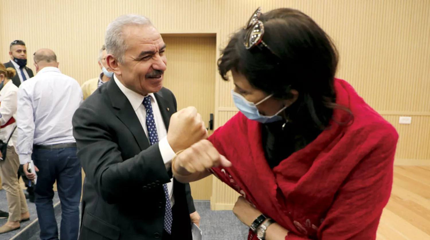 رئيس الوزراء الفلسطيني محمد أشتية يصافح صحافية على الطريقة «الكورونية» خلال مؤتمر صحافي في رام الله الأسبوع الماضي (رويترز)