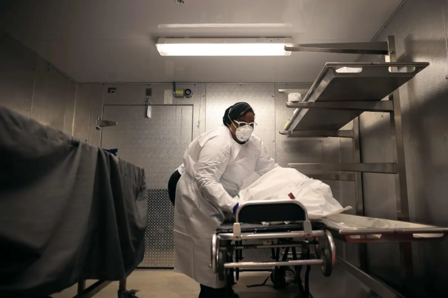 موظفة تنفل جثة أحد ضحايا كورونا إلى مشرحة في ماريلاند بالولايات المتحدة (أ.ف.ب)