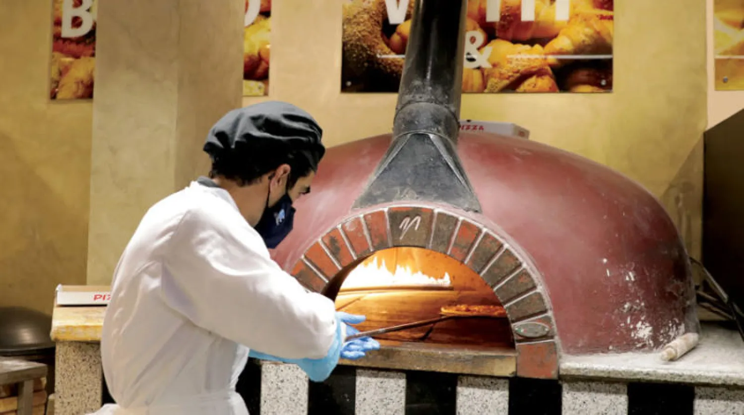 لاجئ سوري يصنع البيتزا في فرنه بالعاصمة الأردنية عمان أمس (أ.ب)
