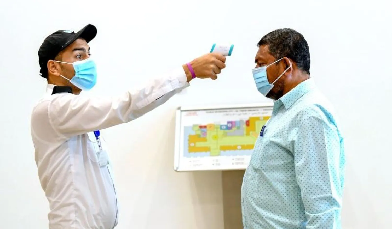 Güvenlik görevlisi bir kişinin ateşini ölçüyor (AFP)
