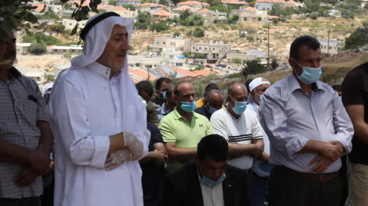 فلسطينيون يضعون كمامات خلال صلاة الجماعة في قرية قرب سلفيت بشمال الضفة الغربية أول من أمس (إ.ب.أ)