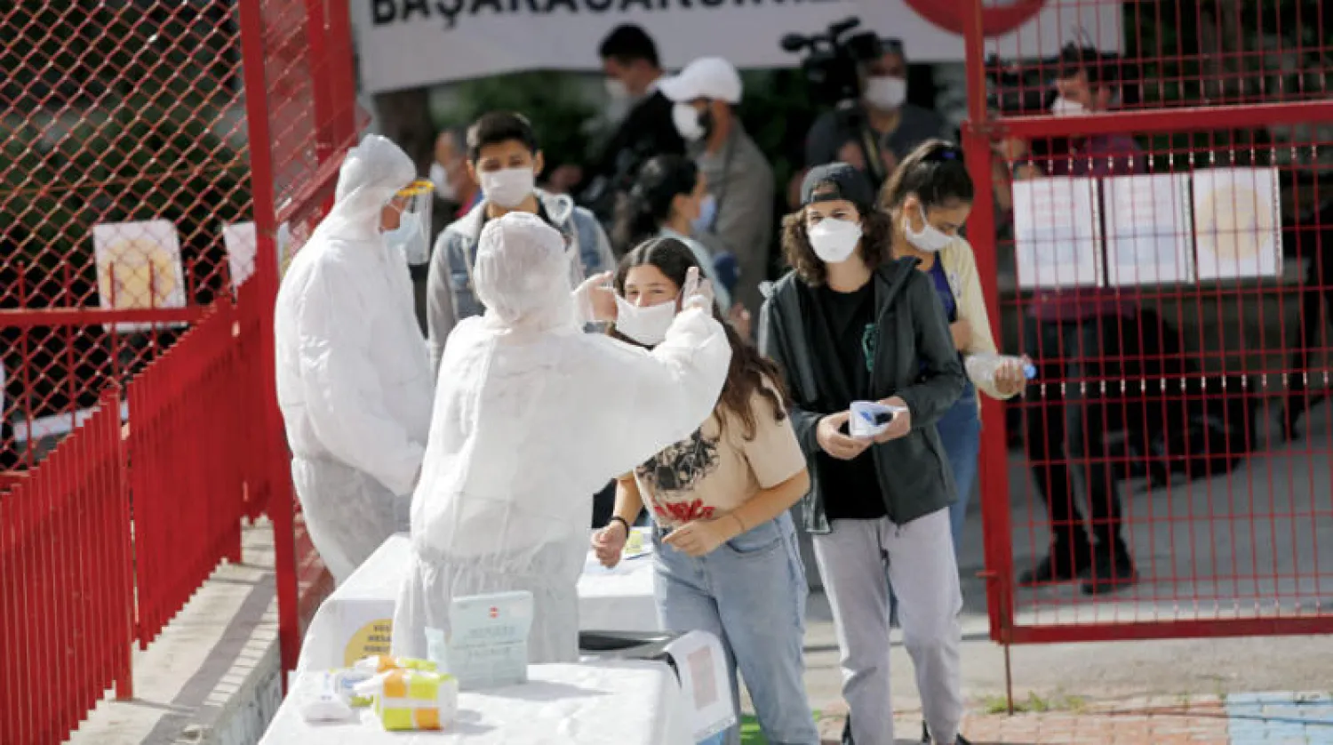 عمال صحة يعقمون أيادي طلاب الثانوية ويوزعون كمامات قبل إجراء الاختبارات في أنقرة أمس (إ.ب.أ)