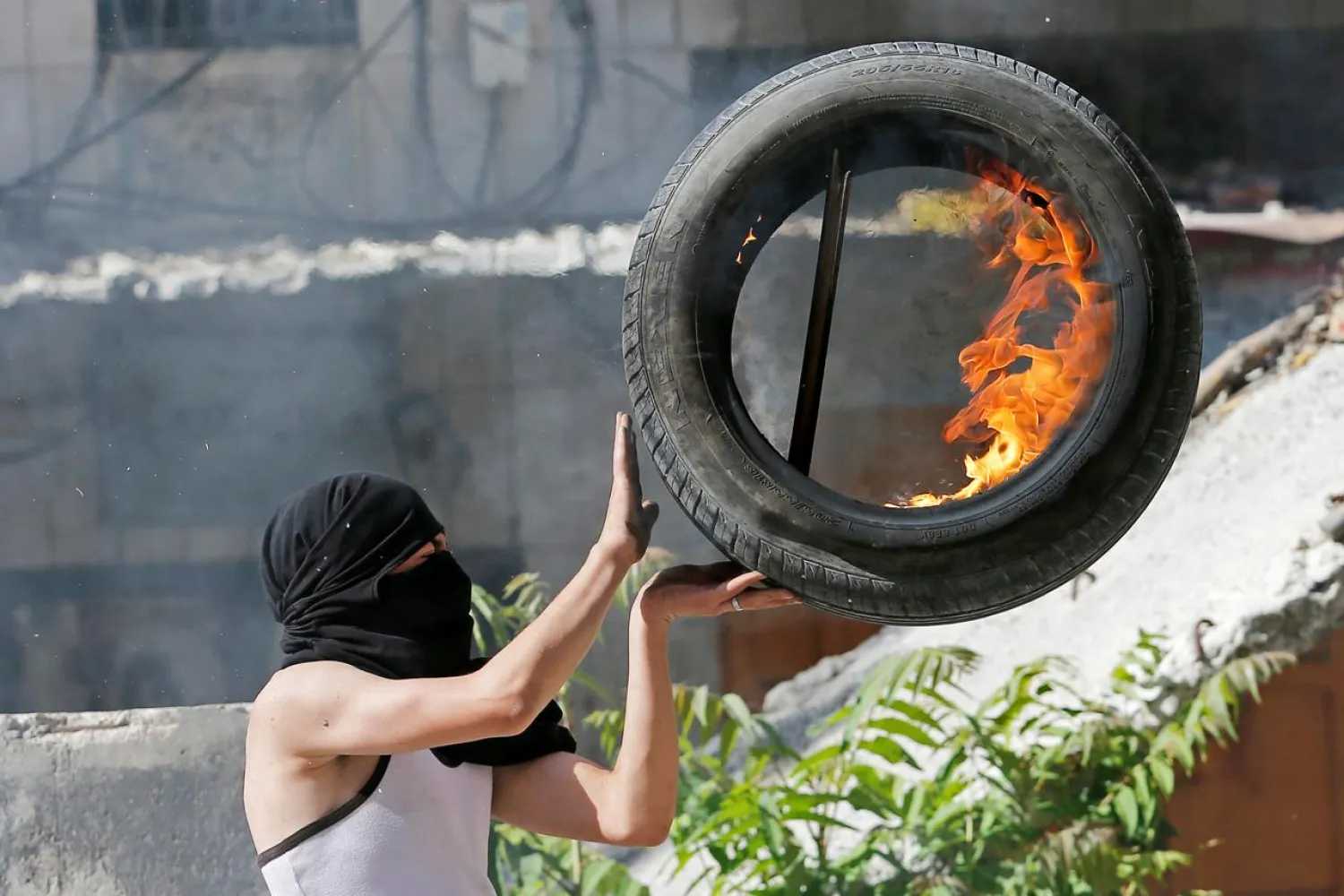 A Palestinian holds a burning tire during a protest against Israel's plan to annex parts of the occupied West Bank, in Hebron June 12, 2020. REUTERS/Mussa Qawasma