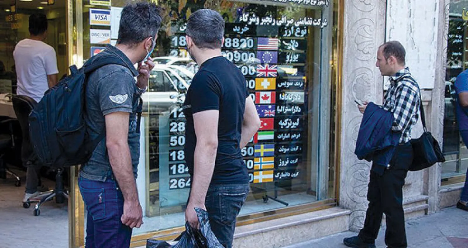 إيرانيون يتابعون تطورات أسعار العملة أمام دار صرافة في طهران (تجارت نيوز)