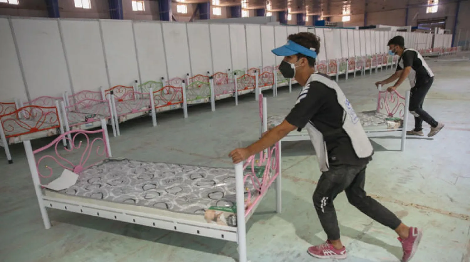 متطوعان يشاركان في تجهيز مستشفى ميداني لمرضى «كورونا» على أرض معرض بغداد الدولي (أ.ف.ب)