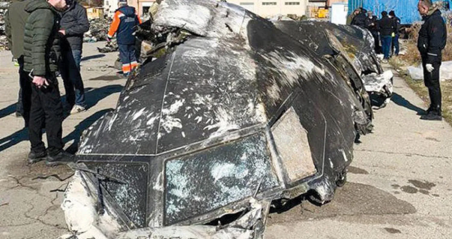 محققون من أوكرانيا يفحصون جزءاً من حطام الطائرة المنكوبة في طهران يناير الماضي (أ.ف.ب)