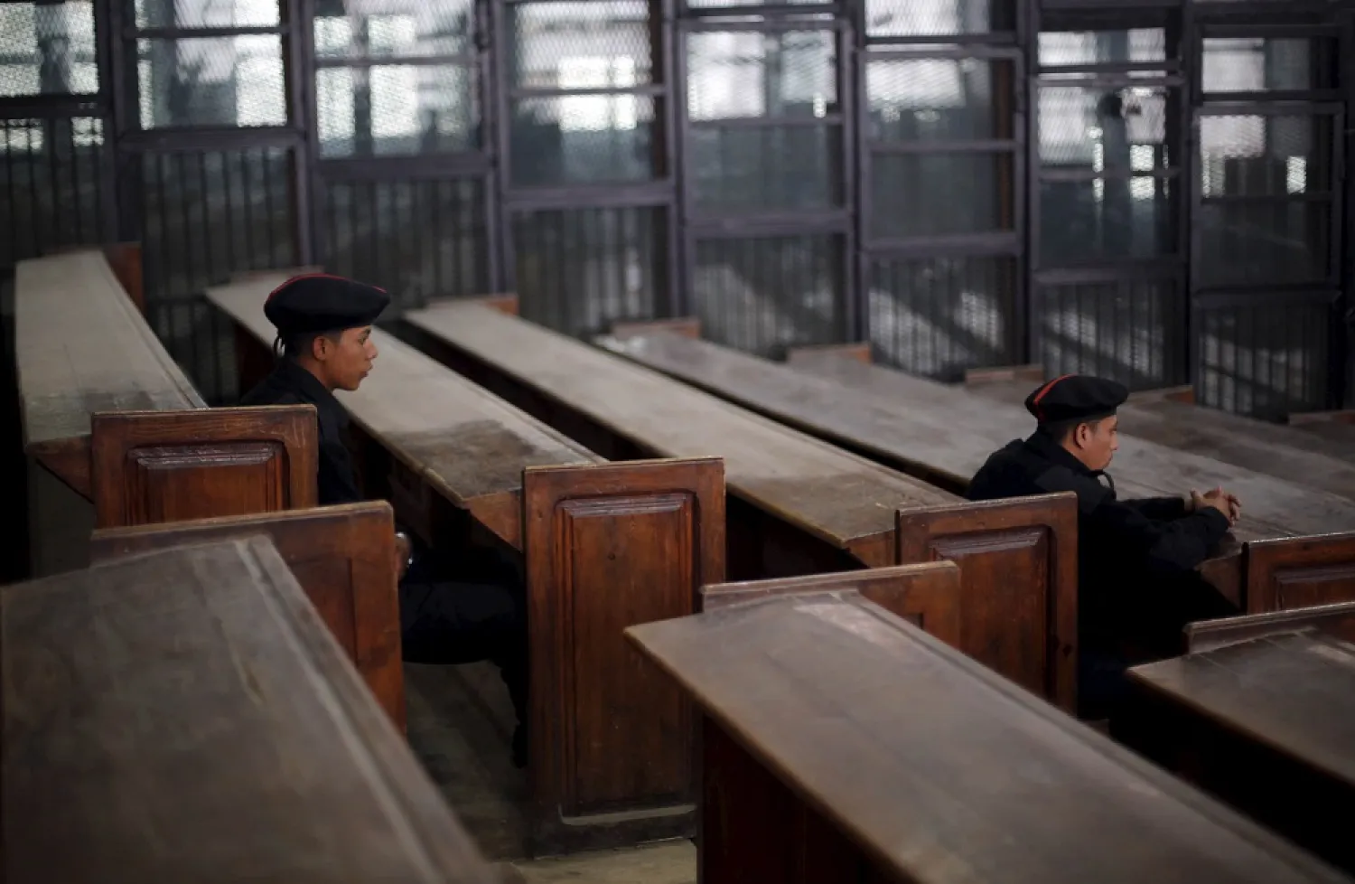 Policemen sit in front of empty bars during the trial of Muslim brotherhood leaders in Cairo. (Reuters)