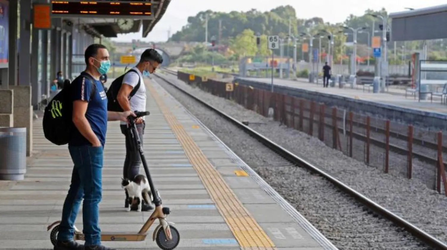 İsrail’de bir tren istasyonunda virüsten korunmak için maske takan iki adam (AFP)