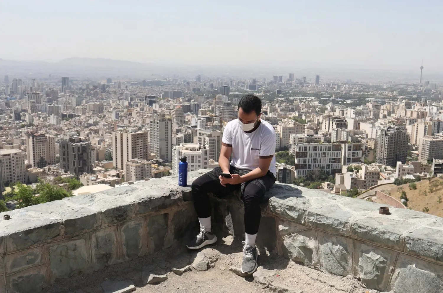 An Iranian man wearing a protective face mask checks his mobile in Baam-e, following the outbreak of the coronavirus, in Tehran. (Reuters)
