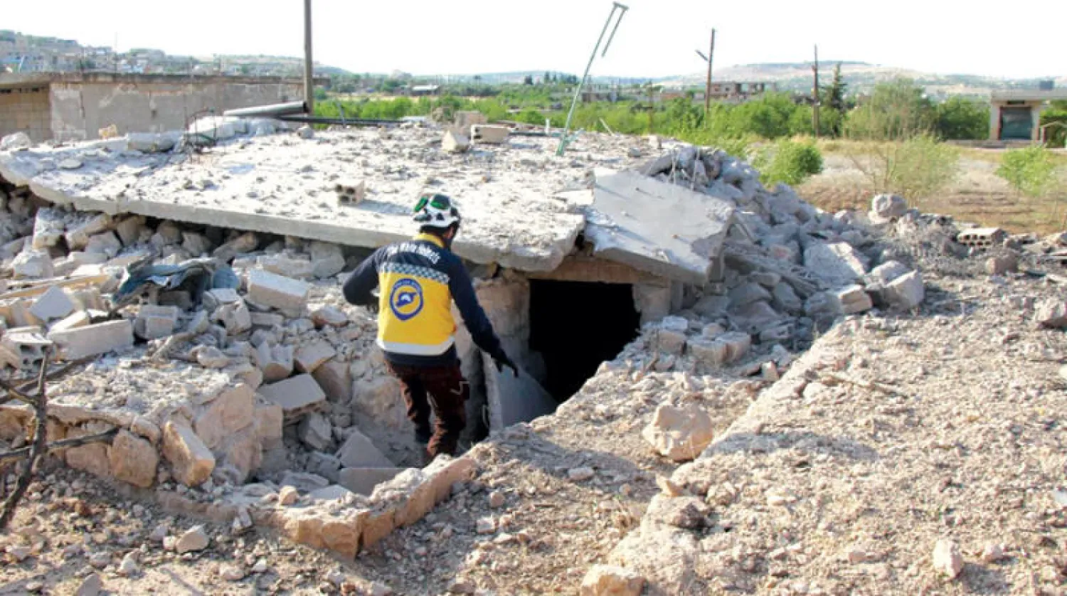 عنصر من الدفاع المدني قرب مبنى مدمر في ريف ادلب (الائتلاف السوري)