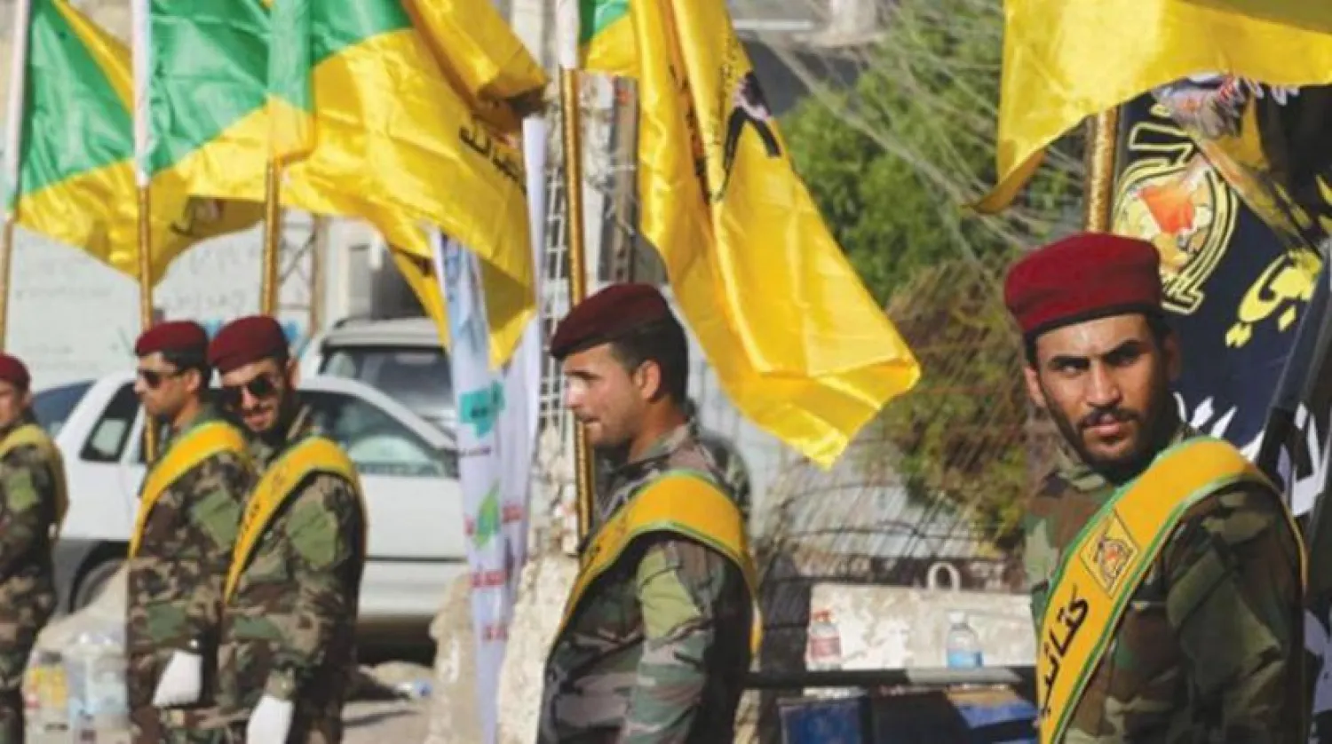 Bir etkinliğe katılan Irak Hizbullah Tugayları’nın sarı renkli bayrakları (Arşiv-Şarku’l Avsat)