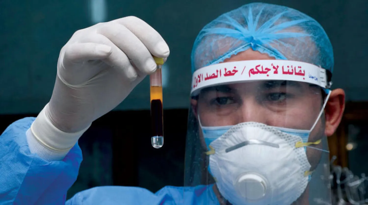 موظف بالقطاع الصحي يفحص عينة دم من مريض مشتبه في اصابته بفيروس «كورونا» في مستشفى بمدينة الناصرية عاصمة محافظة ذي قار جنوب العراق (أ.ف.ب)