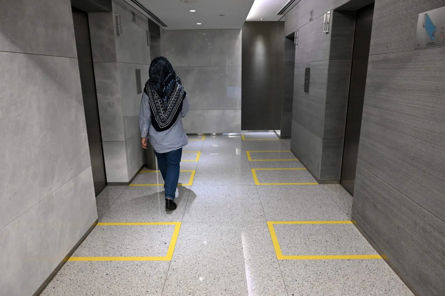 Taped-off areas demarcate safe distances between people in the elevator lobby of an office building in Singapore on March 31, 2020. Roslan Rahman/AFP via Getty Images