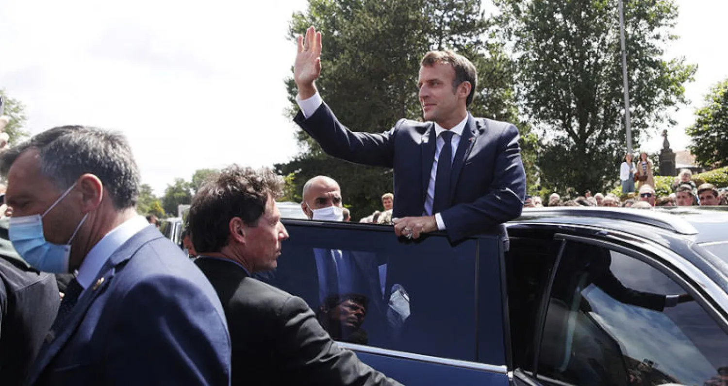 ماكرون يحيّي من السيارة حشداً بعد الإدلاء بصوته في الانتخابات البلدية بباريس أمس (رويترز)