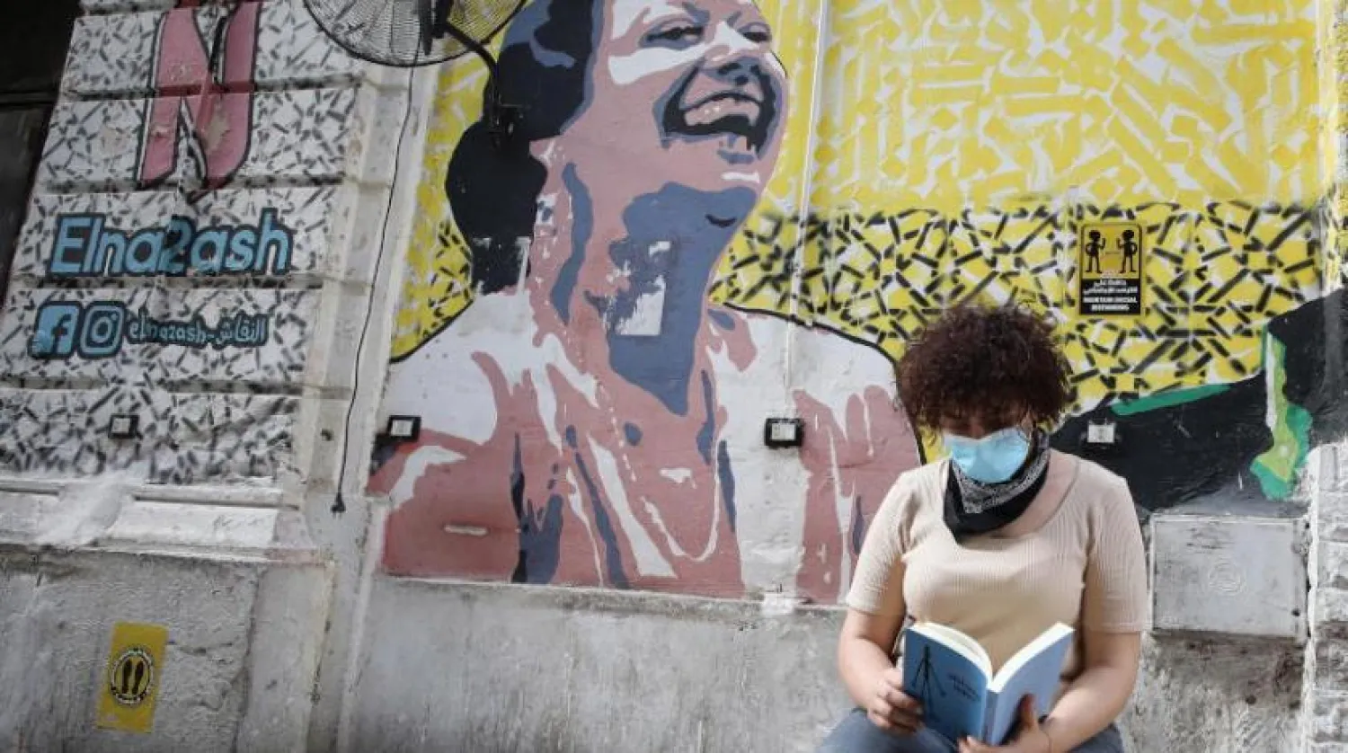 Kahire’de bir kafede maske takan bir kitap okuyor (EPA)