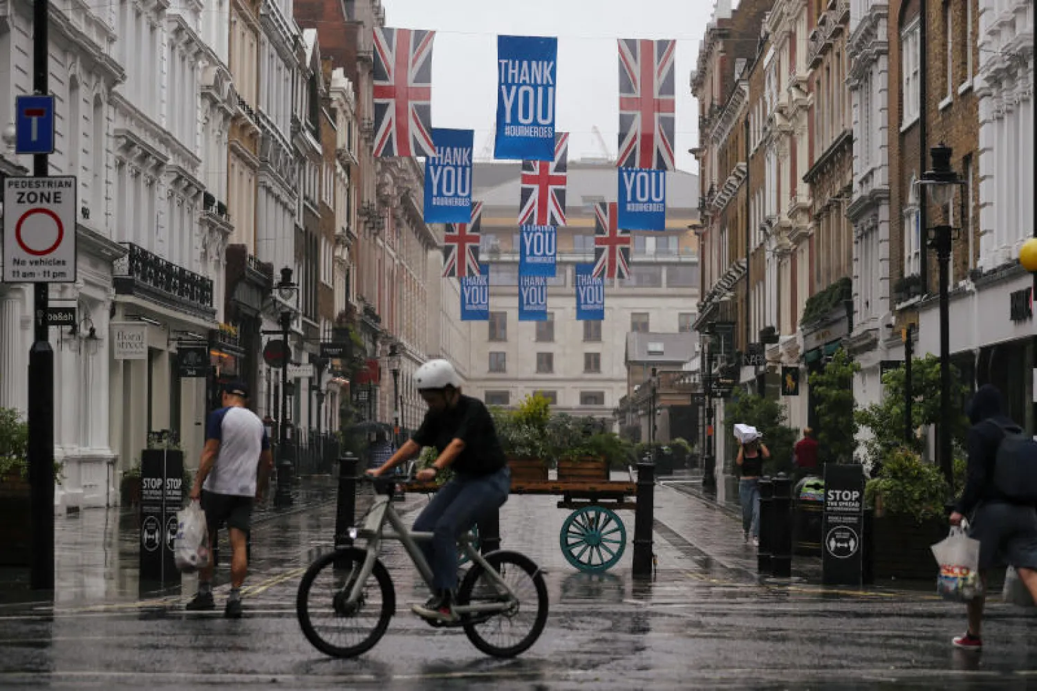 مارة وراكب دراجة في أحد شوارع لندن خلال الإغلاق (رويترز)