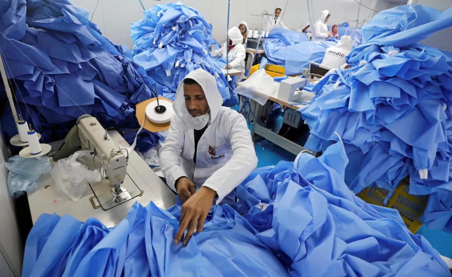 A man sews coats in a factory that produces sterilized surgical equipment and medical clothing, as Egypt ramps up efforts to slow the spread of coronavirus disease (COVID-19), in Sadat, Egypt, March 15, 2020. REUTERS/Mohamed Abd El Ghany