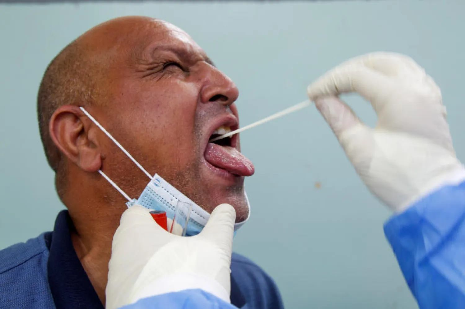 أحد أفراد الطاقم الطبي يخضع لاختبار الكورونا في العراق (رويترز)