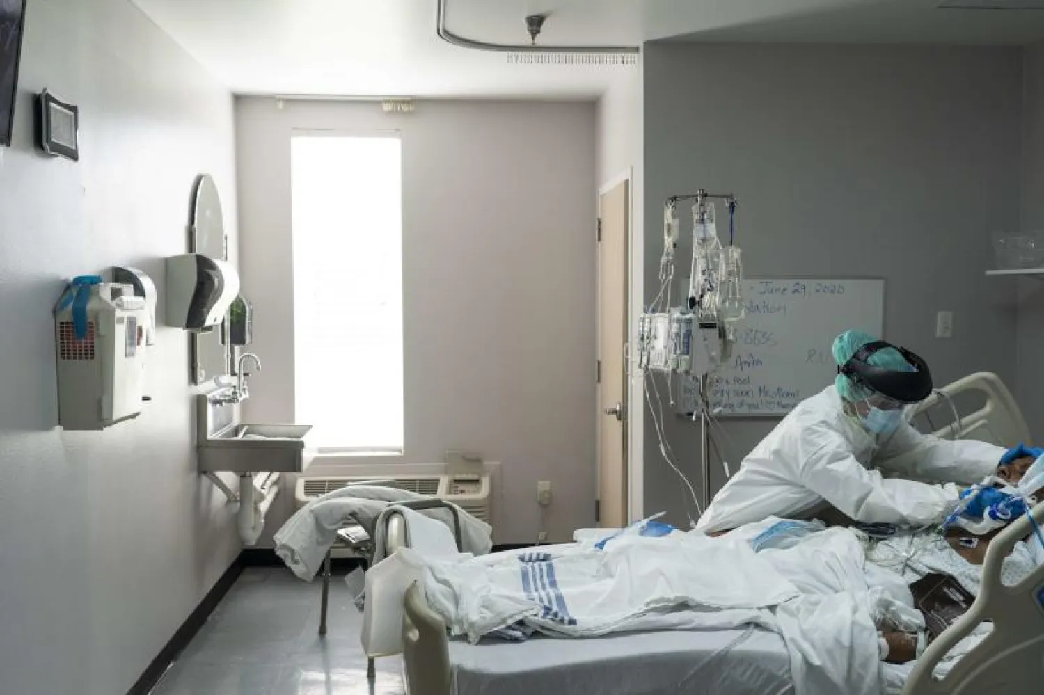 موظف يقوم بمساعدة مريض مصاب بكورونا في أحد مستشفيات تكساس بالولايات المتحدة (أ.ف.ب)