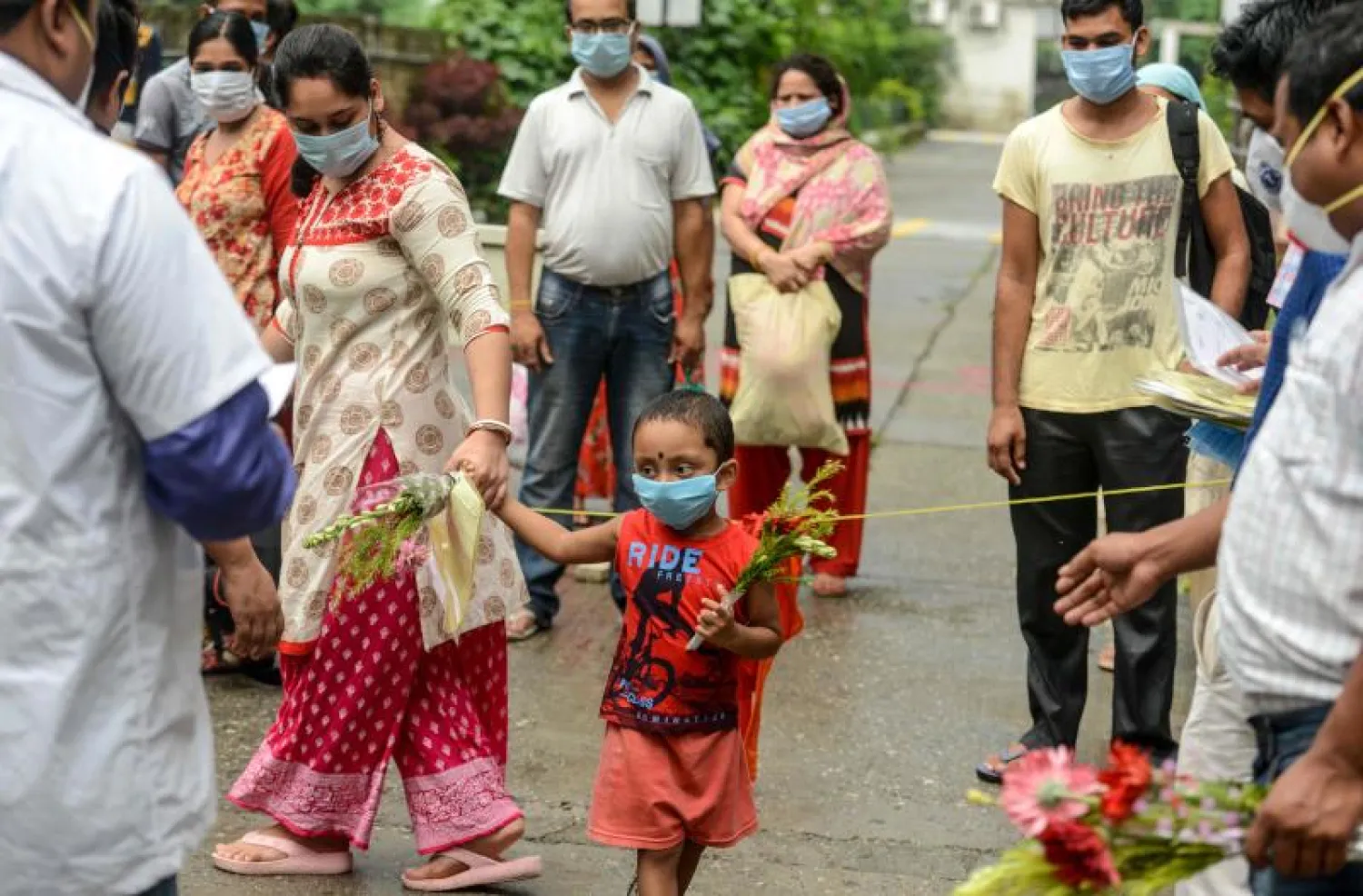 طاقم صحي هندي يوزع شهادات وورود لمتعافين من «كوفيد - 19» في سيليغوري الأربعاء (أ.ف.ب)