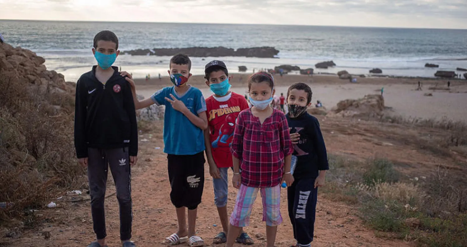 أطفال مغاربة بكماماتهم قرب شاطئ الرباط (أ.ب)