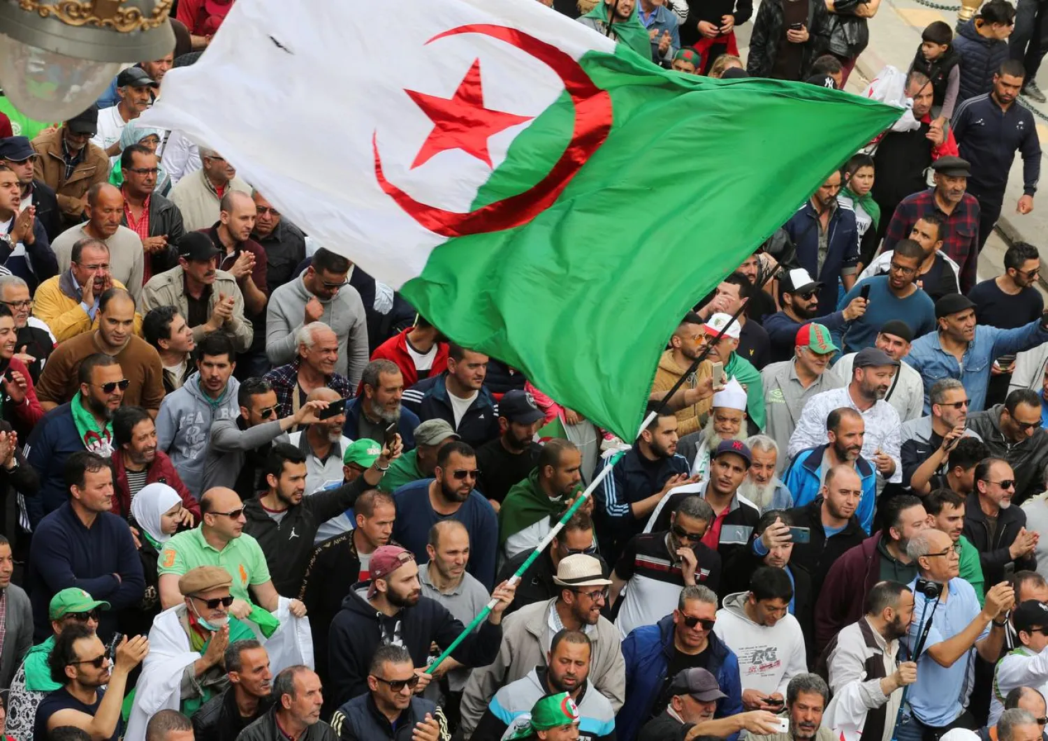 A demonstrator carries a national flag during an anti-government protest in Algiers, Algeria March 13, 2020. REUTERS/Ramzi Boudina