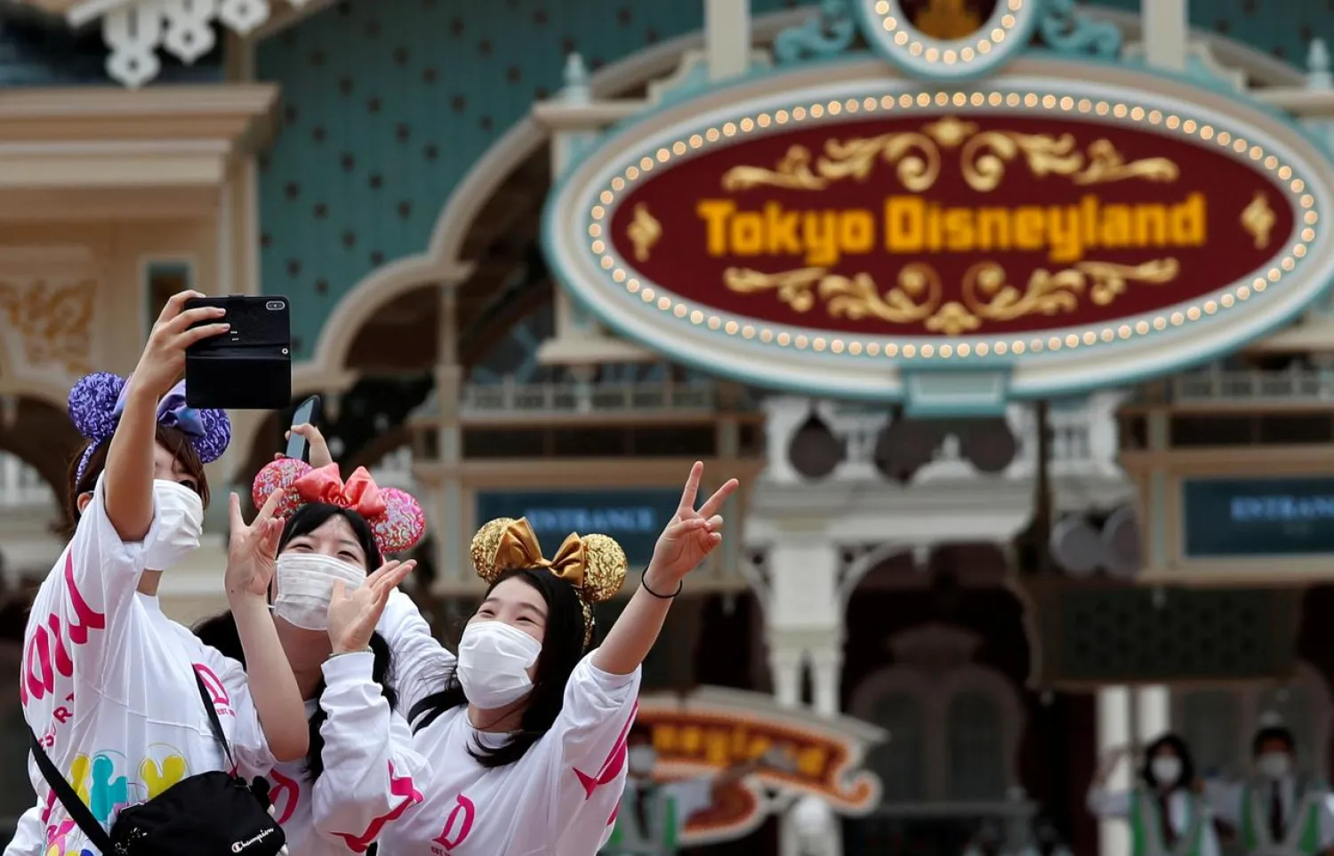 Visitors take a photo after the reopening of Tokyo Disneyland at the entrance gate of Tokyo Disneyland in Urayasu, east of Tokyo, Japan July 1, 2020. (Reuters)