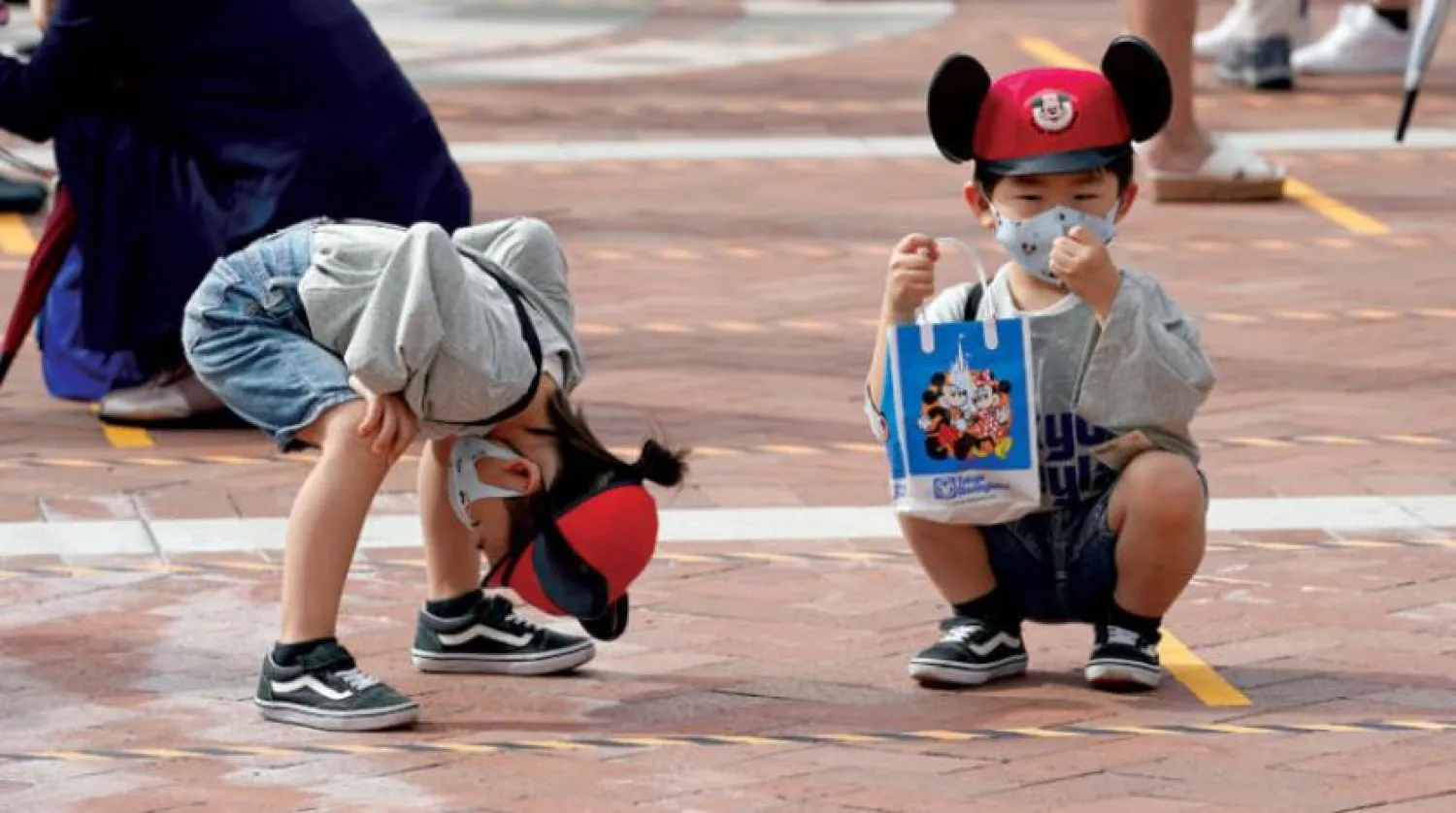Dün Japonya'nın Chiba Eyaletindeki ‘Disneyland’ girişinde maske takan iki çocuk (EPA)