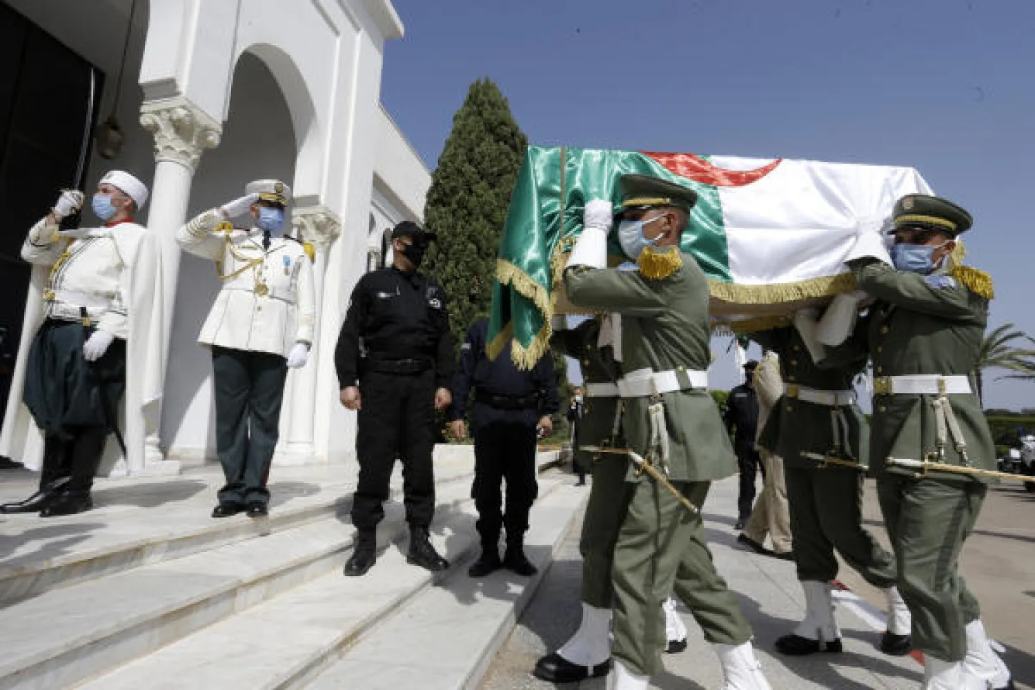 The remains of 24 Algerians are carried by members of the Algerian Republican Guard at the Moufdi-Zakaria culture palace in Algiers, Friday, July, 3, 2020. (AFP)