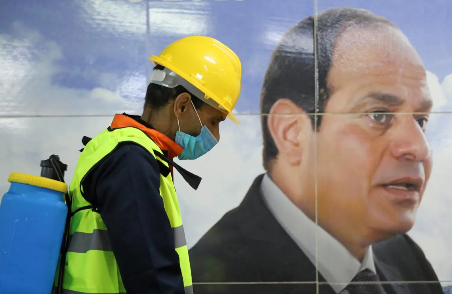 A member of a medical team sprays disinfectant as he passes an image of President Sisi, Cairo, March 22, 2020. (Reuters)