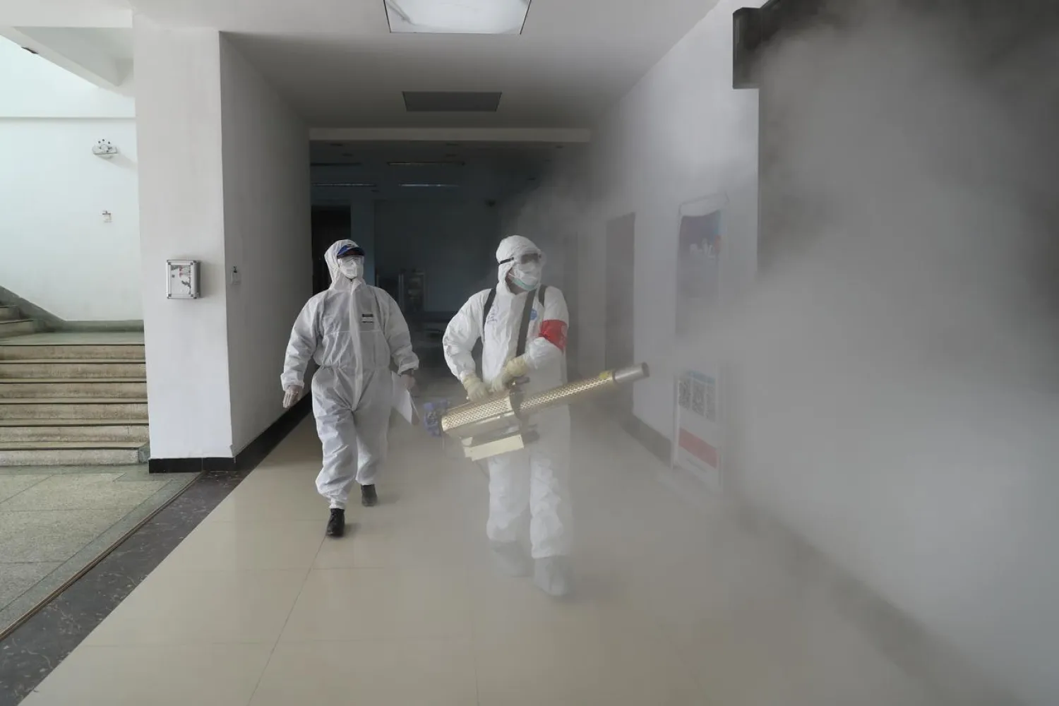 Volunteers in protective suits disinfect a residential compound in Wuhan, the epicenter of the novel coronavirus outbreak, in Hubei province, China February 22, 2020. Picture taken February 22, 2020. China Daily via REUTERS