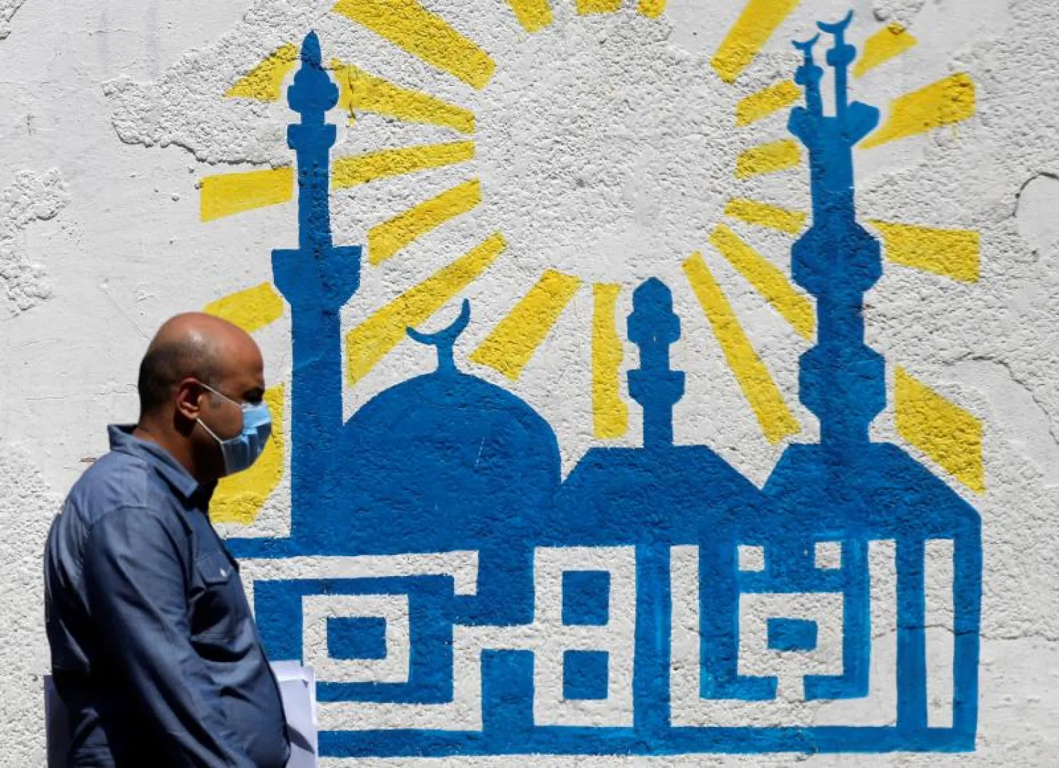 رجل يمر من أمام جدارية تحمل اسم القاهرة في أحد شوارع العاصمة المصرية (رويترز)