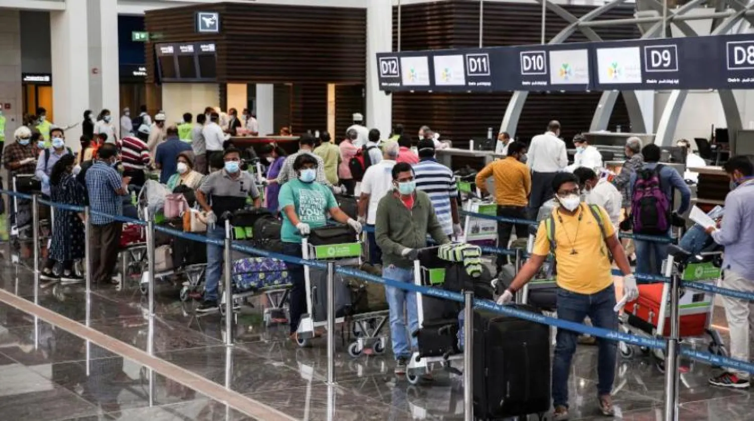Indian nationals residing in Oman, wearing face masks due to the coronavirus pandemic, queue with their luggage at the check-in counter at a terminal in Muscat International Airport ahead of their repatriation flight from the Omani capital, on May 12, 2020. (Photo by MOHAMMED MAHJOUB / AFP)