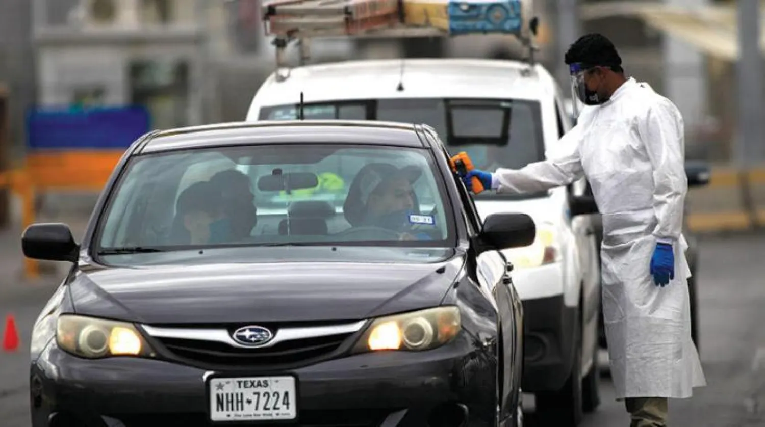 ABD’de Cebu-Cordova Köprüsü üzerinde sürücülerin ateşini ölçen bir sağlık görevlisi (EPA)